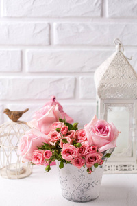 粉红色玫瑰花和装饰灯笼对白色砖墙。花静物。选择性对焦。文本位置