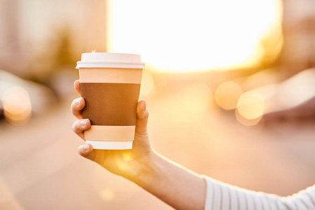 年轻女孩拿着纸杯与热咖啡在日落