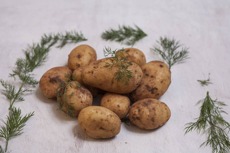 白色的木制背景上的新鲜原料土豆。顶视图