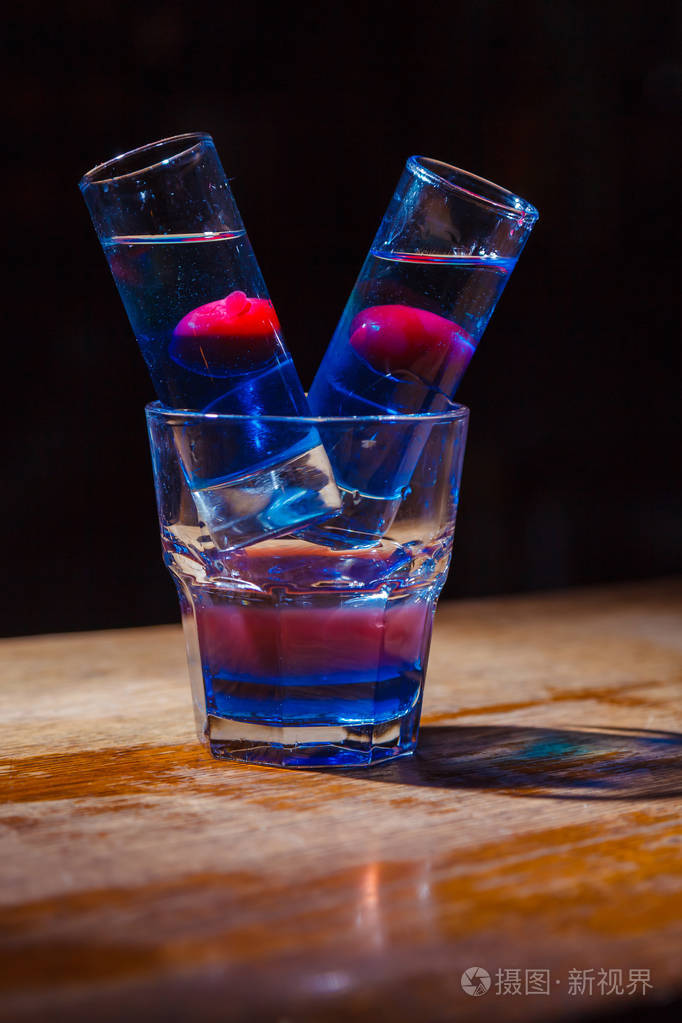 带有红色和蓝色层和樱桃的异国情调鸡尾酒特写