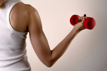 高关键性感健身模式运动员女子手与红色哑铃在灰色演播室背景.