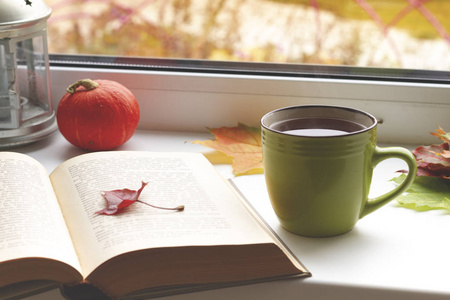 秋天静物。书, 叶子, 杯子和烛台在窗口