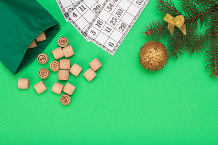 棋盘游戏。木莲花桶与包和游戏卡的游戏在, 圣诞冷杉树枝和玩具球在绿色的背景。顶视图