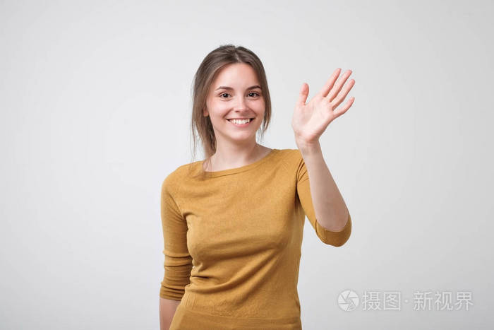身着黄色 pulover 的欧洲少年穿着漂亮的衣服打招呼 挥舞着她的手.