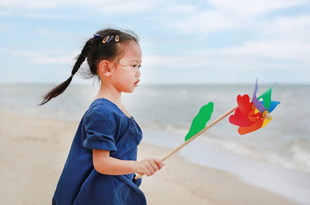快乐的小女孩看着海上手持风车在海上海岸