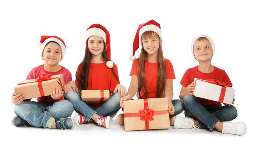 可爱的小孩子在圣诞老人帽子与圣诞节礼物在白色背景