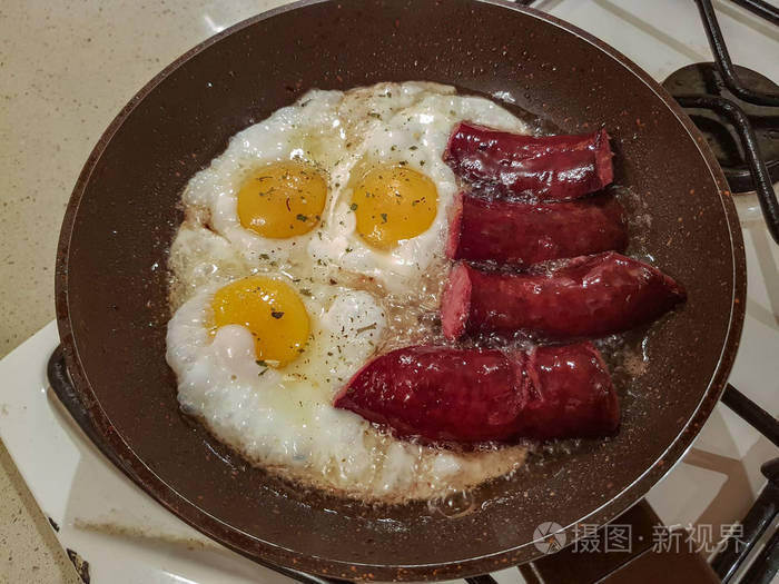 早餐的开胃熏香肠和鸡蛋煎在油煎锅里