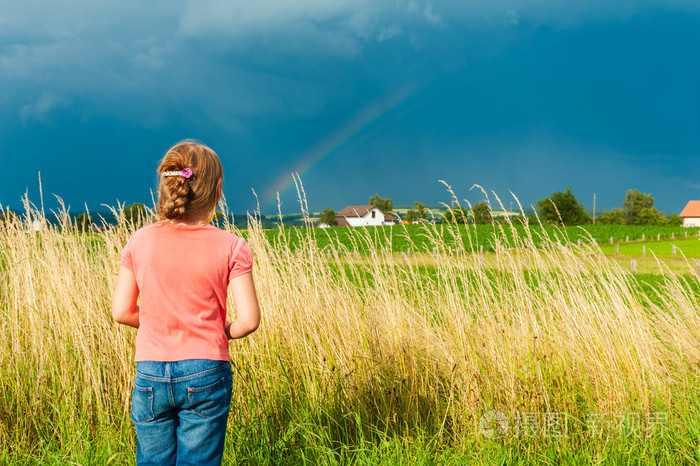 可爱的小女孩,并遥望远方在美丽的乡村美好的夏天一天