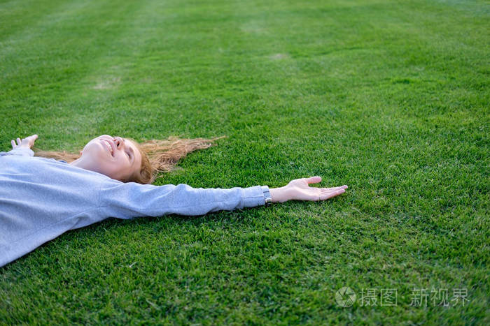 红发白人年轻女子躺在足球场草坪上 ralaxing