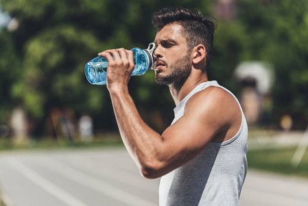 运动的年轻人喝水在锻炼以后