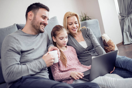 美丽幸福的家庭与孩子看笔记本电脑与微笑