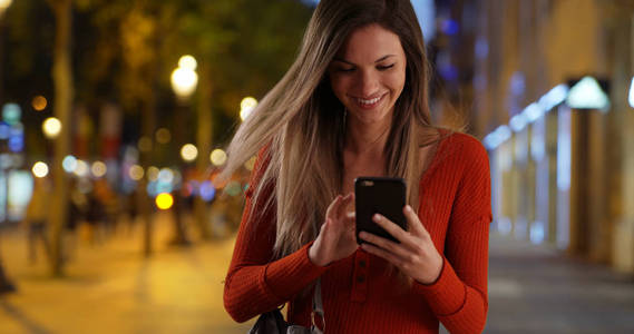 年轻女士从袋子里掏出智能手机回复香榭丽舍大街上的短信