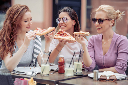 三快乐的女孩在户外咖啡馆吃比萨饼。人食物饮料和生活方式概念