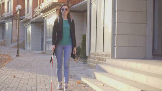 一个盲人女孩的肖像与拐杖走在街上