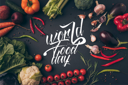 在灰色的桌子上, 有世界食品日字母的未加工蔬菜的顶视图