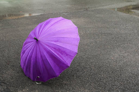 伞紫色在路和雨下落与拷贝空间为添加文本