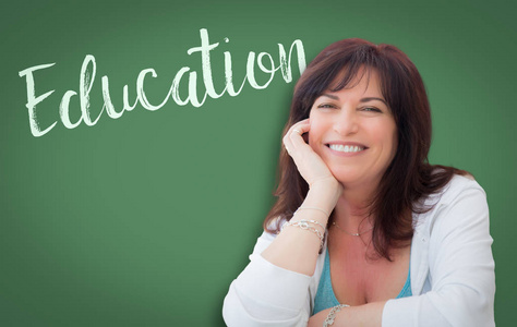 在微笑中年妇女背后的绿色黑板上写的教育