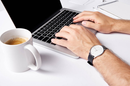 使用膝上型咖啡的人在白色表面的前景上用笔记本电脑打字的镜头
