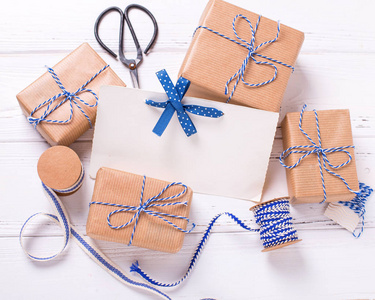 空标签和包装礼品盒与礼物和蓝色丝带在纹理的木质背景