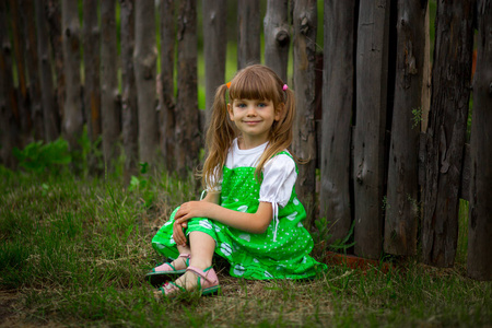 阳光明媚的夏日, 坐在园林绿草上的小女孩