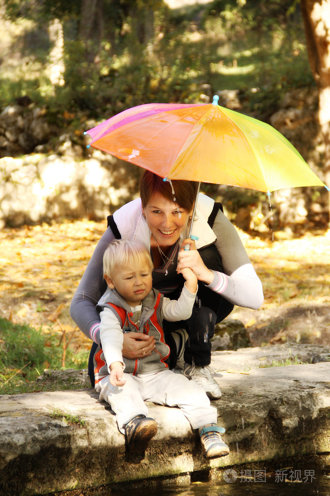 妈妈带着孩子在公园的伞下
