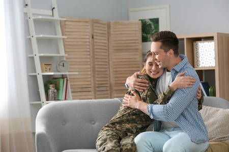 妇女在军事制服与她的丈夫在沙发在家