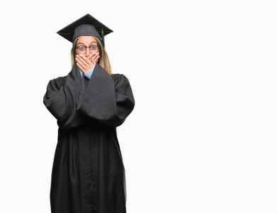 年轻漂亮的女子穿着毕业制服在孤立的背景下震惊地捂着嘴巴, 误了手。秘密概念