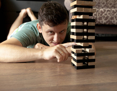 男子玩木游戏积木在家里。教育风险发展和成长的概念