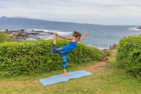 在毛伊岛夏威夷风景秀丽的海岸上练习瑜伽的妇女