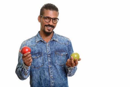 快乐印度小伙子手持红色和绿色的苹果