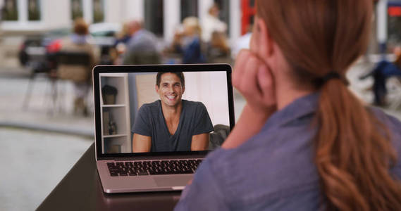 年轻的高加索妇女与白人男子在笔记本电脑上的视频对话