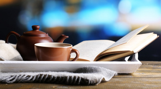 喝杯热茶茶壶和书放在明亮的背景上的桌子上