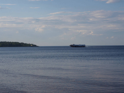 一艘快艇穿过湖面, 在天空和绿色森林的背景下穿行。