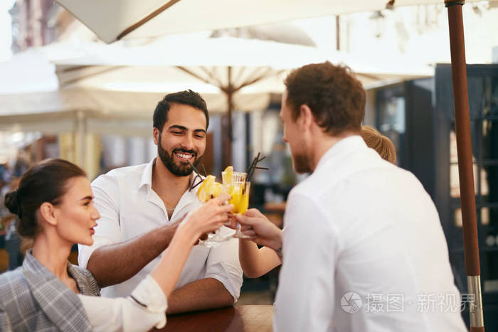 朋友们庆祝在户外酒吧喝酒快乐的微笑的人欢呼与鸡尾酒在咖啡馆高