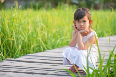 亚洲可爱的女孩放松坐在木桥上的稻田在稻田上日落与自然背景