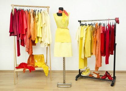 衣柜带黄色 橙色和红色的衣服，安排在衣架和模特儿身上的黄色外套