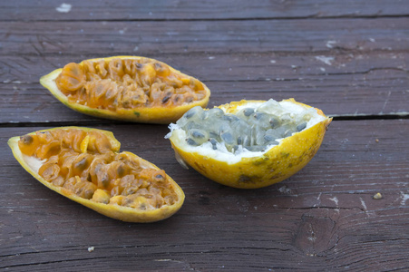 香蕉西番莲和柠檬西番莲水果在木桌上, 一半水果准备吃, 水果果肉种子