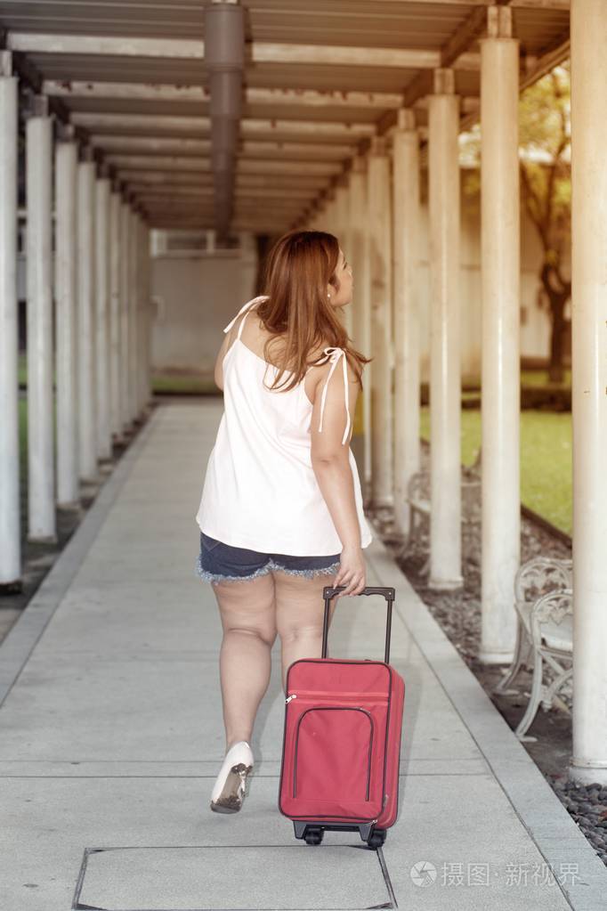 亚洲漂亮的胖女人在人行道上姿势走路和拿行李