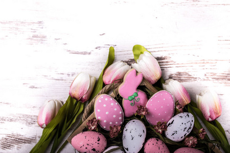 复活节姜饼饼干和木桌上美丽的郁金香花束。兔子和鸡蛋。贺卡。从上面看。复制空间