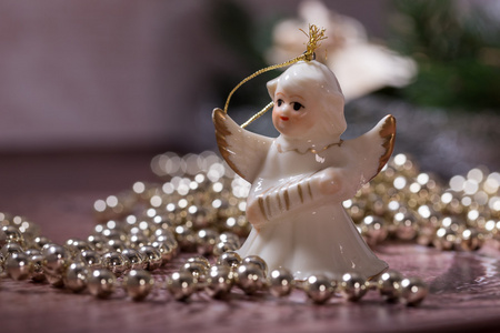 陶瓷天使和躺在木桌上的金黄色的光泽圣诞链