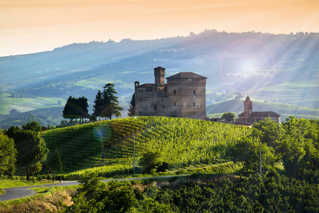 在日落的 Grinzane 加富尔的城堡, 天空是黄色和橙色和一些阳光照亮庄园在背光