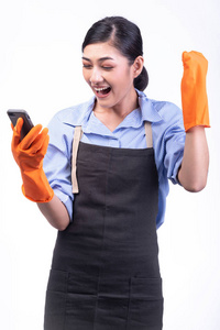 房屋清洁服务妇女查出的白色。亚洲年轻女子用手套, 使用手机, 大赢姿势。网上房屋清洁服务概念
