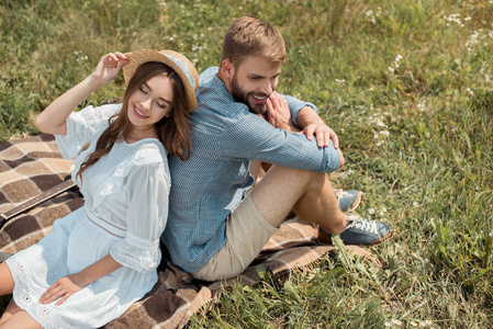 高角度的微笑夫妇休息回到后面的毯子在野外与野生花卉在夏季日