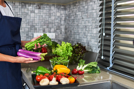 女人的手在厨房洗涤水槽里的蔬菜。健康饮食理念