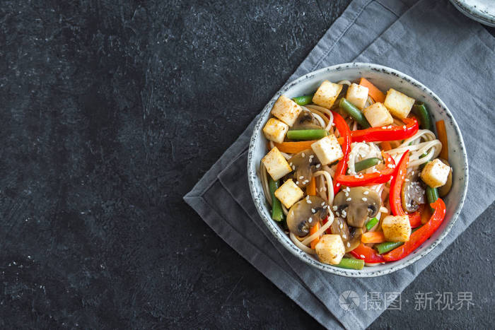 用乌冬面条豆腐蘑菇和蔬菜炒。亚洲素食素食, 膳食, 炒黑背景, 复制空间
