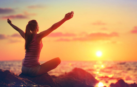 放松和瑜伽在夕阳女孩张开双臂看海洋