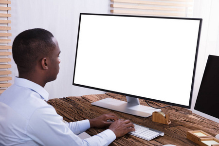 在木桌上用空白白色屏幕的计算机关闭一个商人