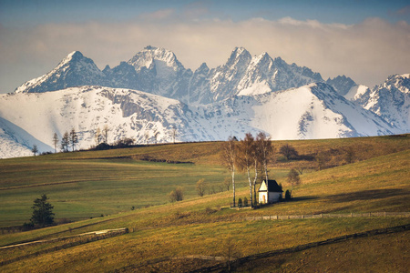 Kacwin, Malopolskie, 波兰的一个教堂和积雪覆盖的 Tatra 山脉的景观