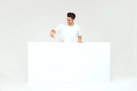 年轻英俊的家伙拿着空白的白色横幅, 招牌, 孤立的白色演播室背景