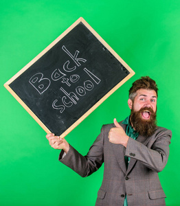 老师高兴地祝贺新学年开学。邀请庆祝知识日。老师胡子人拿着黑板与题字回到学校绿色背景